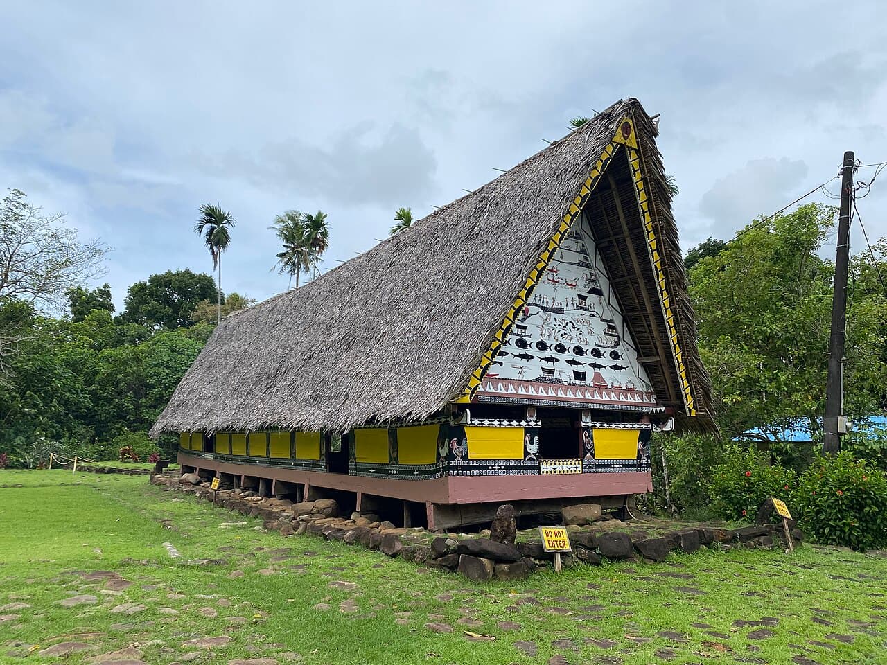 A traditional Palauan bai meeting house with a high gabled roof decorated with colourful painted panels