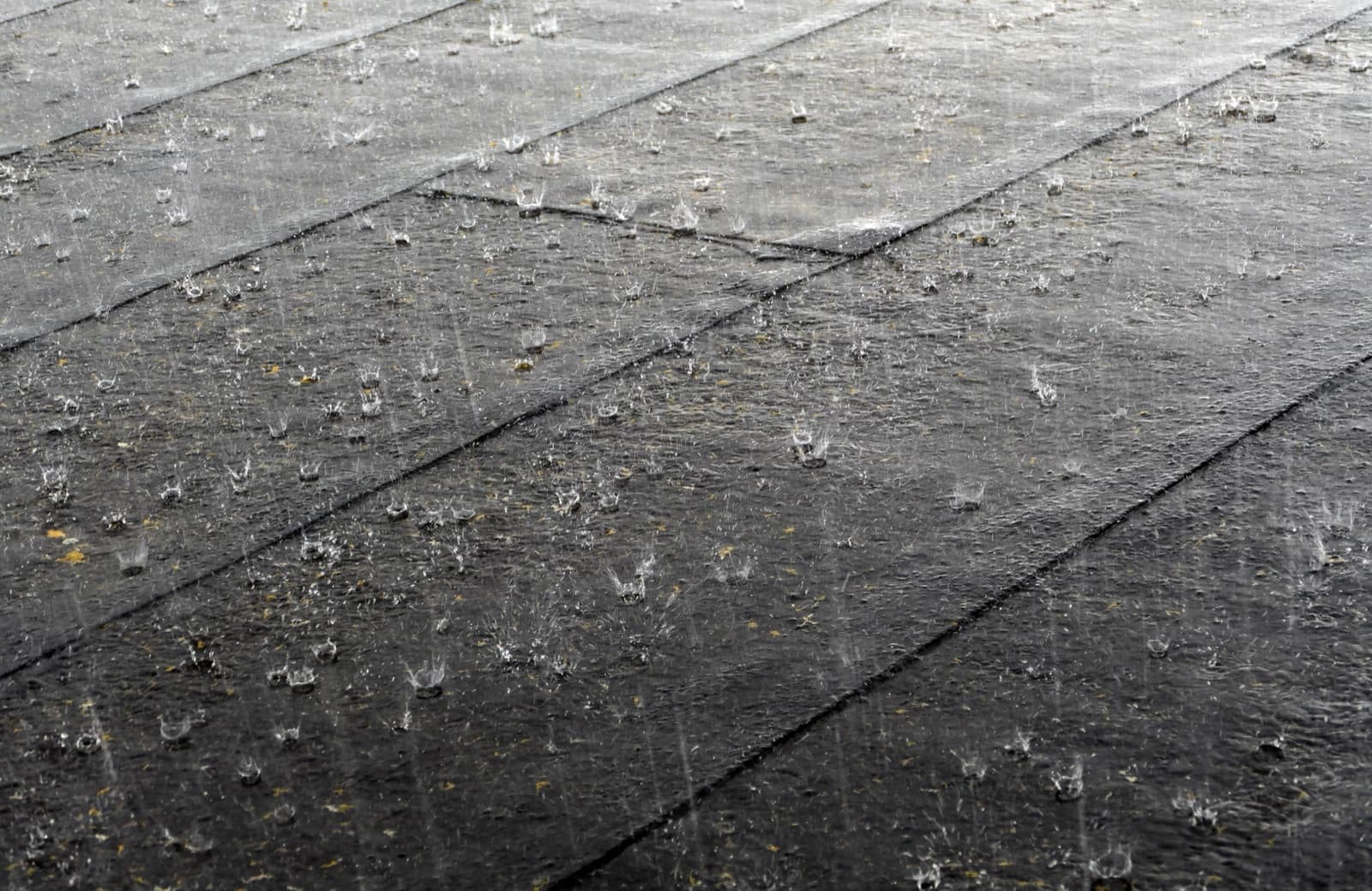 Rain falling hard onto a wet roof, drops bouncing