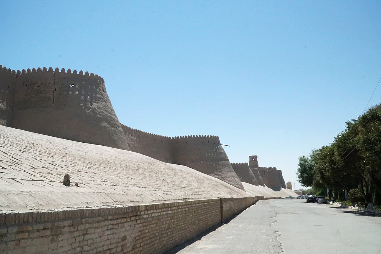 The mud-brick walls and turquoise minaret of Khiva's old town under a blue sky
