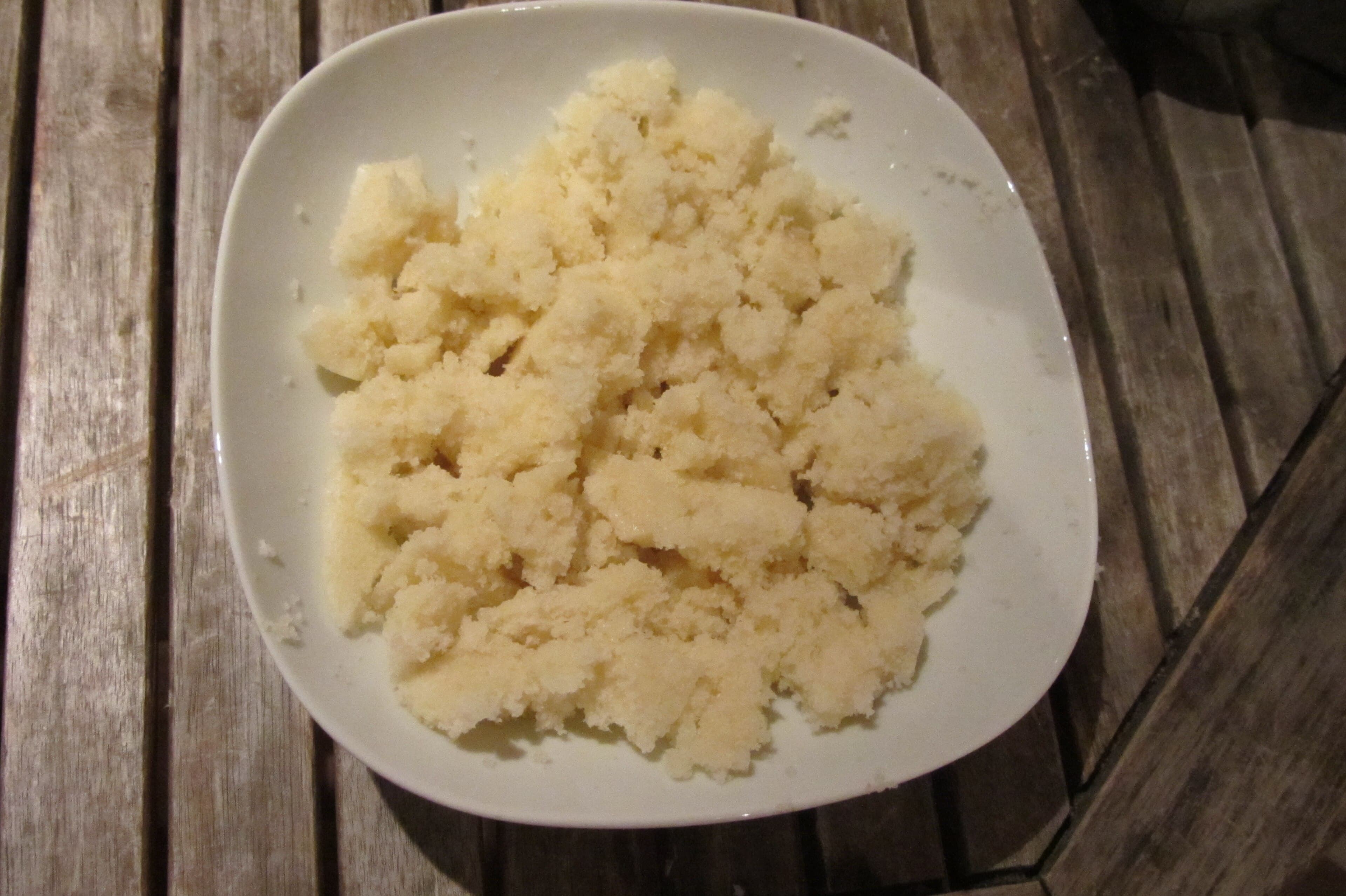 A bowl of fluffy white attiéké cassava semolina on a wooden table