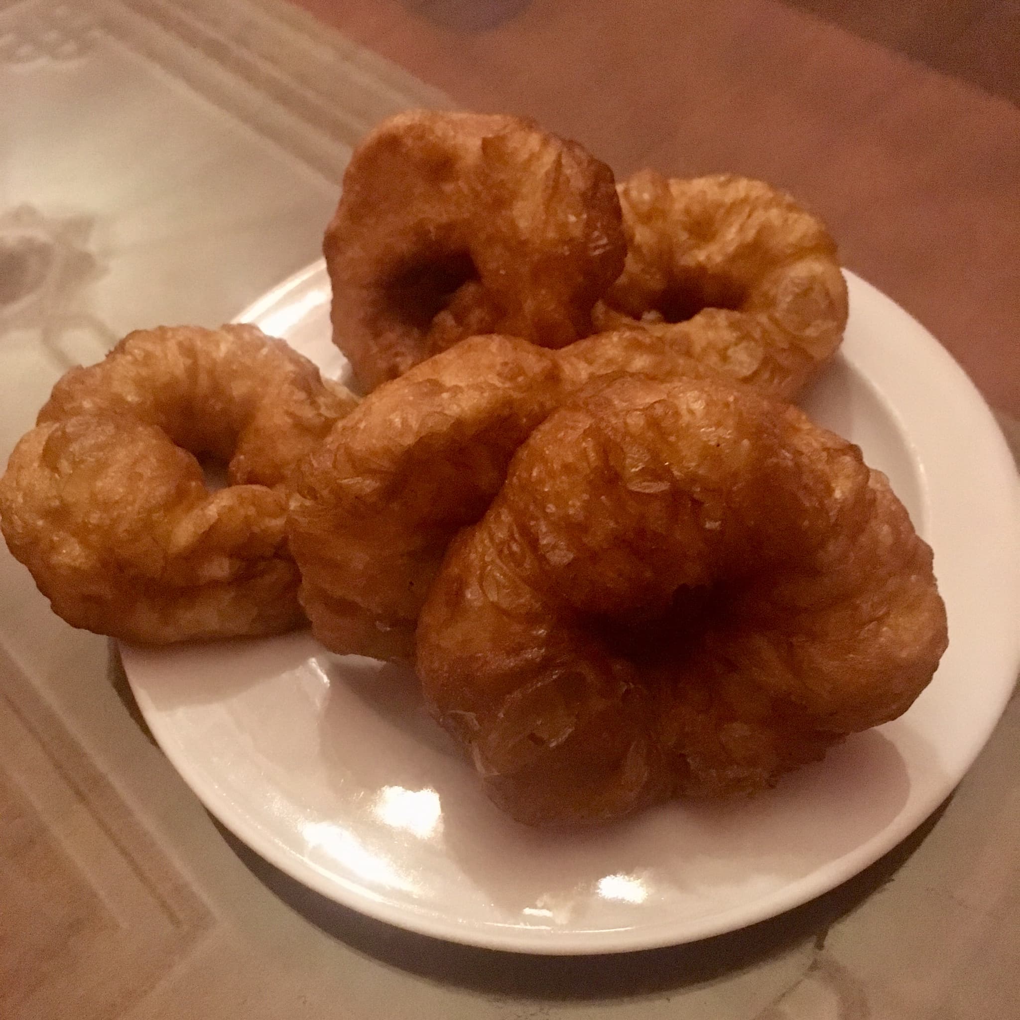 Golden fried sfinz doughnuts in a pile, some drizzled with honey and sprinkled with sesame