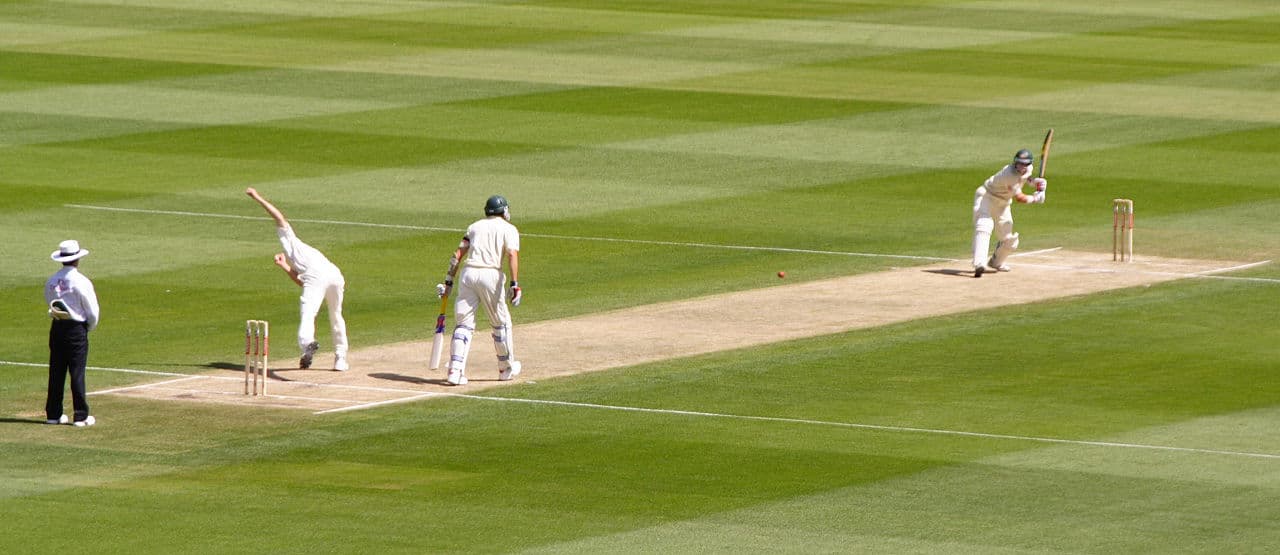 A cricket match being played on a green pitch in Saint Lucia with the sea visible in the background